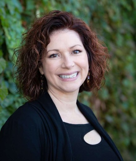 Michelle Edwards, smiling, in front of an ivy-covered wall